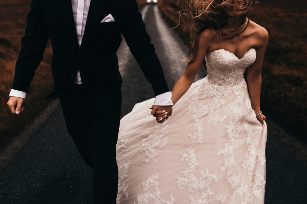 Glen Coe elopement in a wedding dress and suit. Adventurous elopement Glen Evitte in Scotland. Rainy and windy road at Scottish highlands. Traveling couple photosession after the wedding.