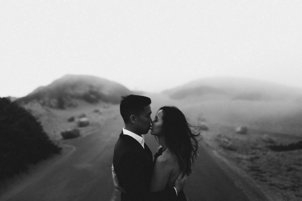 Romantic couple picture at foggy Point Reyes, California. Intimate after wedding photosession. Couple kissing in an embrace.