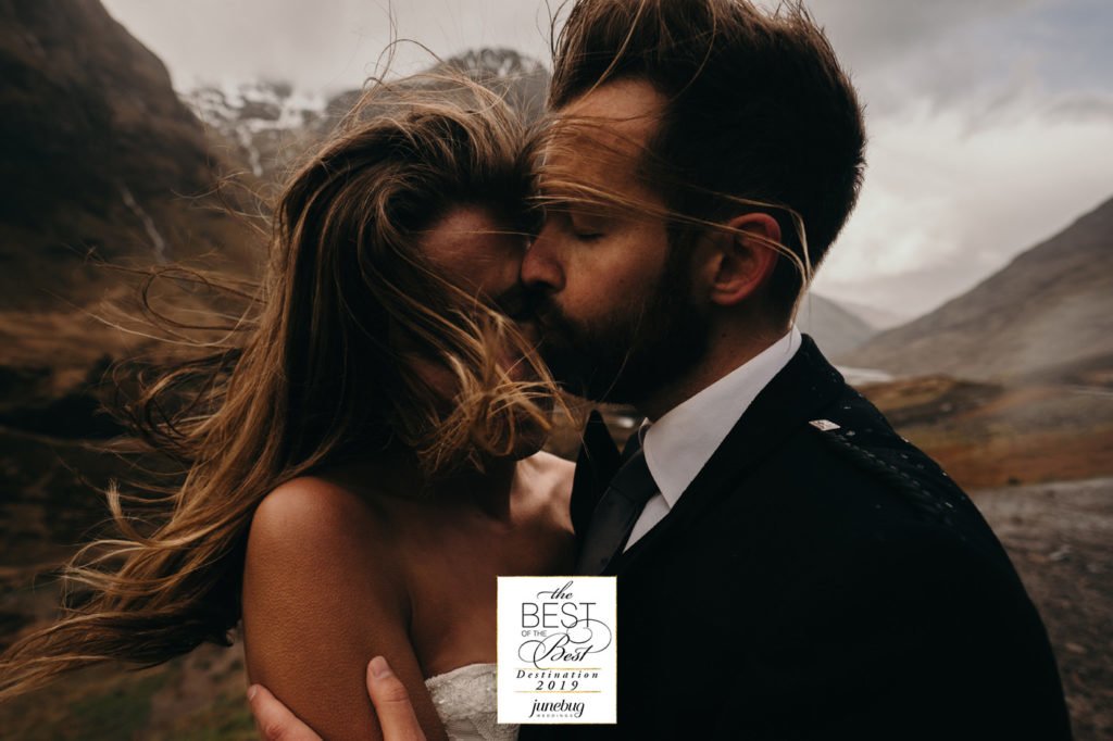 Best wedding and elopement photography by Junebug Weddings. Emotional kiss and embrace in Three Sisters Mountains, Glen Coe, Scotland, UK. After wedding photoshoot. Elopement in highlands in Scotland.