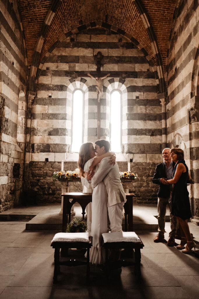 Romantic wedding in medieval church san pietro in portovenere. Getting married in Roman Catholic Saint Peter's church. Couple lighting a candle in a medieval church in Italy. Romantic wedding ceremony.
